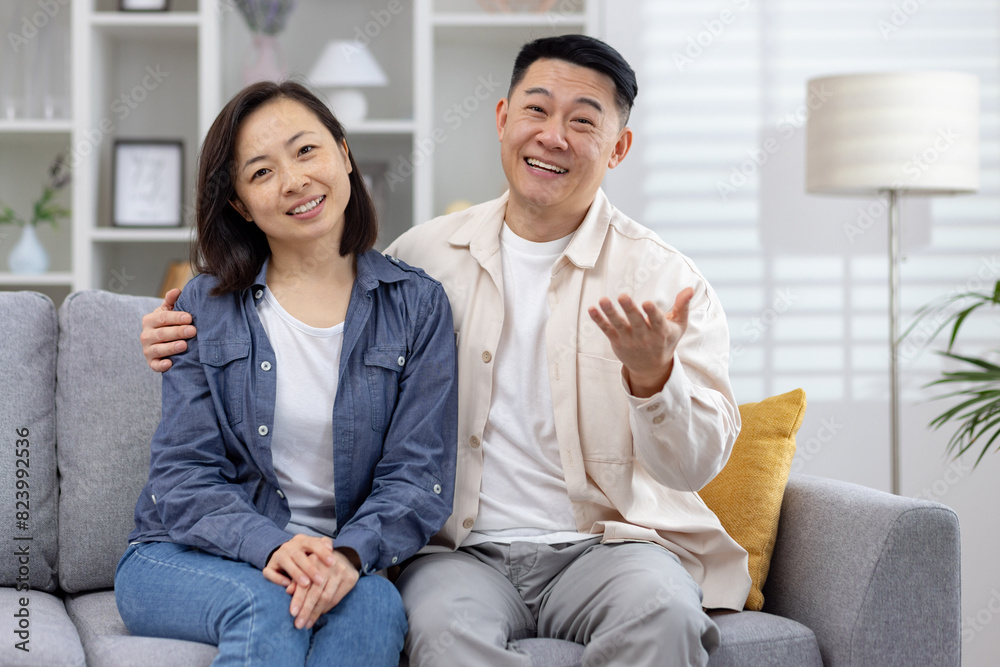 Joyful couple sitting on a cozy sofa at home, smiling and enjoying their time together. Perfect image for family, relationships, and happiness concepts. Joyful couple sitting on a cozy sofa at home, smiling and enjoying their time together. Perfect image for family, relationships, and happiness concepts.