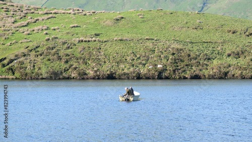 RHYD DDU, CAERNARFON, WALES - MAY 9 2024: People fly fishing from a boat on Llyn Dywarchen with Yr Wyddfa in the background. photo