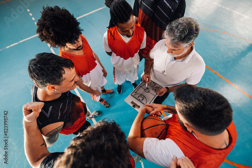 Foto Elderly male coach discussing game tactics with his diverse basketball team