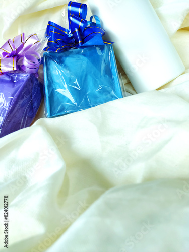 Beautiful colored present boxes with tied ribbon and cosmetic package on the tissue background. Gift giving concept.
