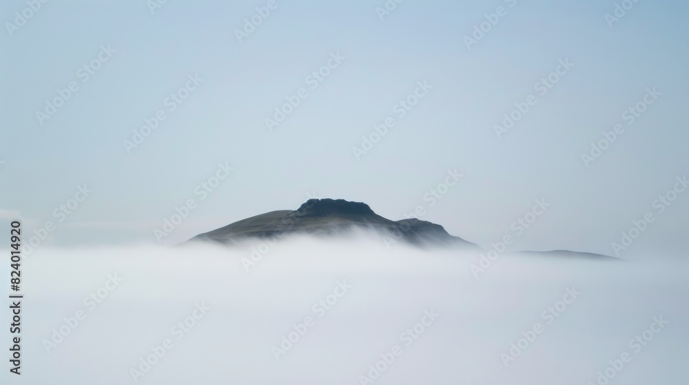 A single hill stands out amidst a blanket of mist, encapsulating minimalism and the serene beauty of simplicity. A single hill stands out amidst a blanket of mist, encapsulating minimalism and the serene beauty of simplicity.