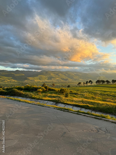 Landscape on sunset with green field of grass with mountains under clouds near Agara in Georgia
