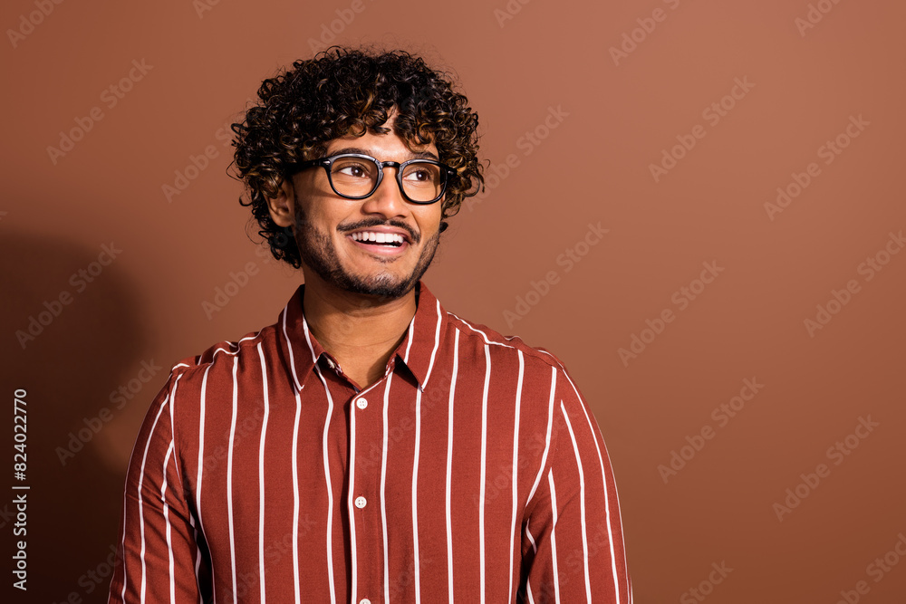 Fototapeta premium Photo of nice young man look empty space wear striped shirt isolated on brown color background