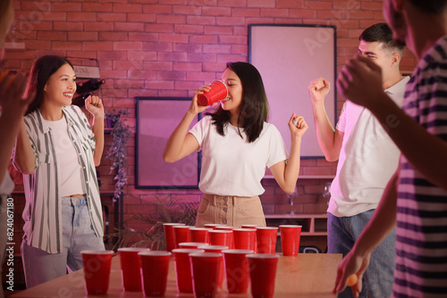 Group of young friends playing beer pong at party