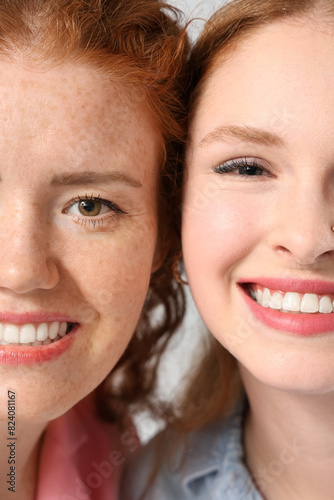 Stylish happy redhead sisters on grey background  closeup