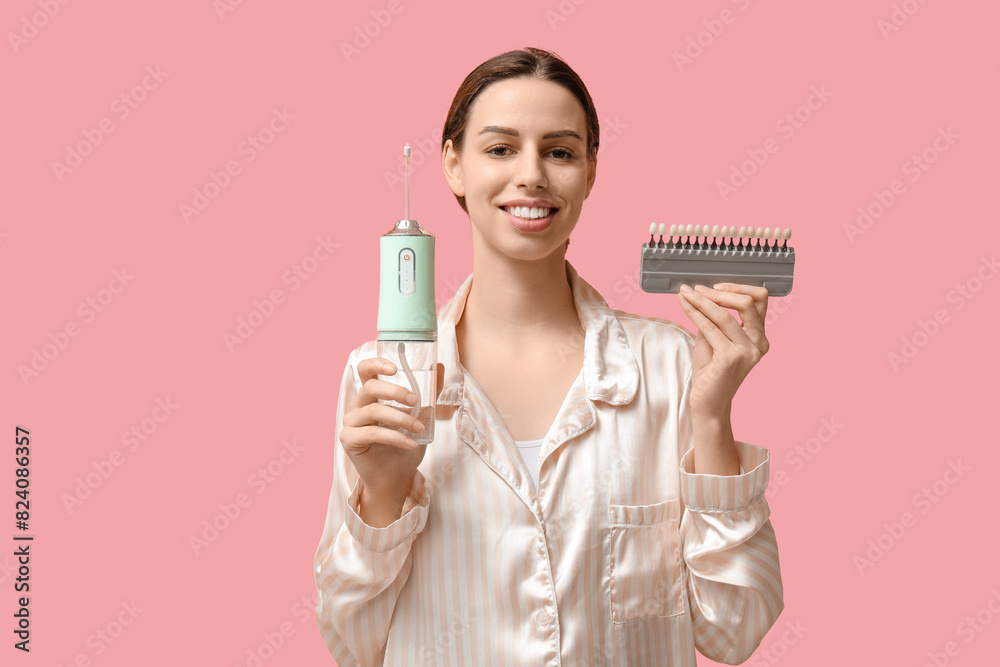 Beautiful young woman with oral irrigator and teeth color samples on pink background Beautiful young woman with oral irrigator and teeth color samples on pink background