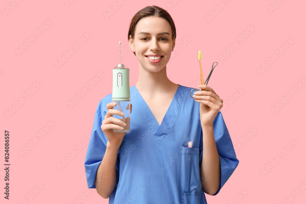 Female dentist with oral irrigator, toothbrush and tool on pink background Female dentist with oral irrigator, toothbrush and tool on pink background