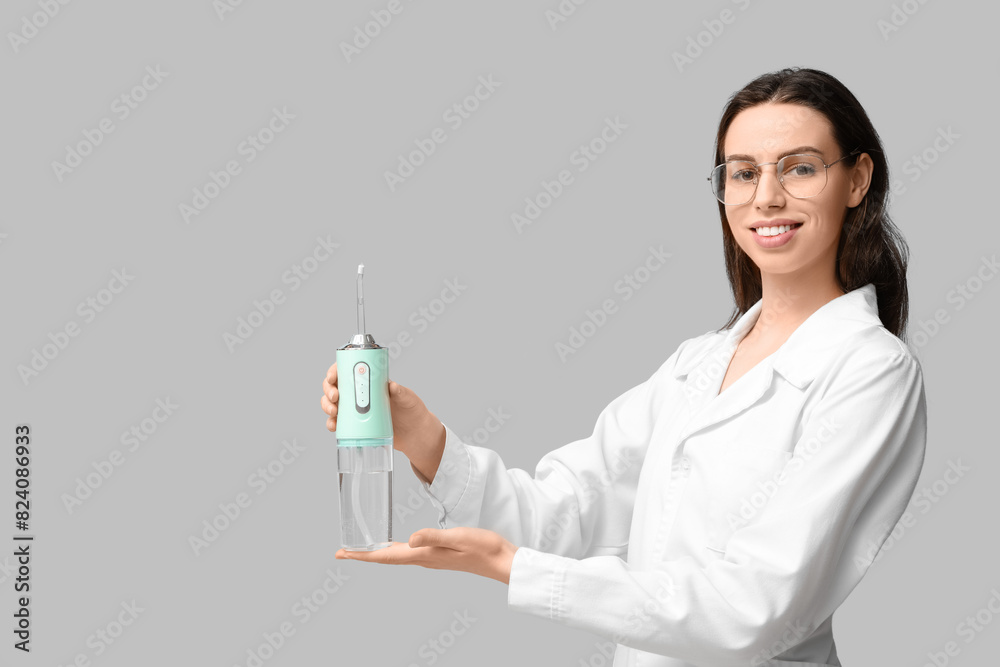 Female dentist with oral irrigator on grey background Female dentist with oral irrigator on grey background