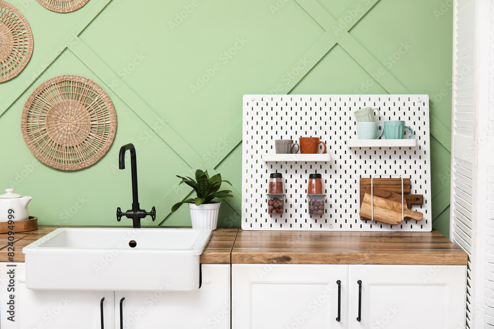 Pegboard, sink and white counters near green wall in kitchen