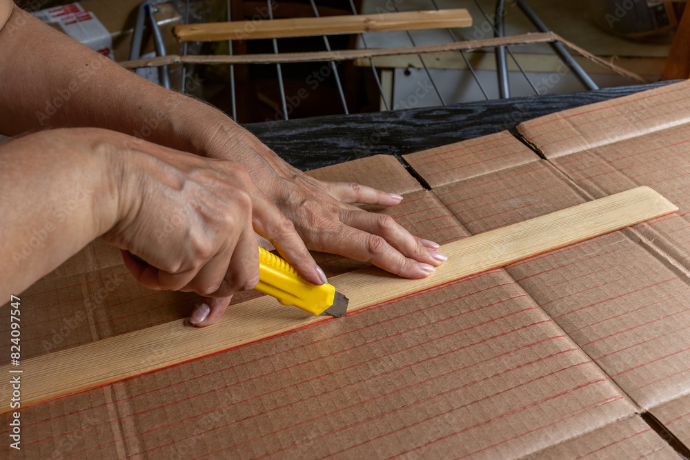 Close-up of woman's hands cutting strips of corrugated cardboard along markings with stationery knife. Concept of recycling packaging into useful household item, DIY. Close-up of woman's hands cutting strips of corrugated cardboard along markings with stationery knife. Concept of recycling packaging into useful household item, DIY.