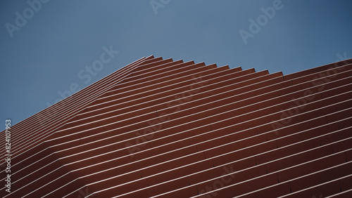 Fotografie Fachada en tonos naranja y tierra en ciudad contemporánea con cielo, y formas ge