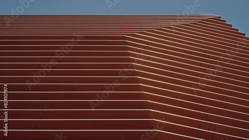 Fotografie Fachada en tonos naranja y tierra en ciudad contemporánea con cielo, y formas ge