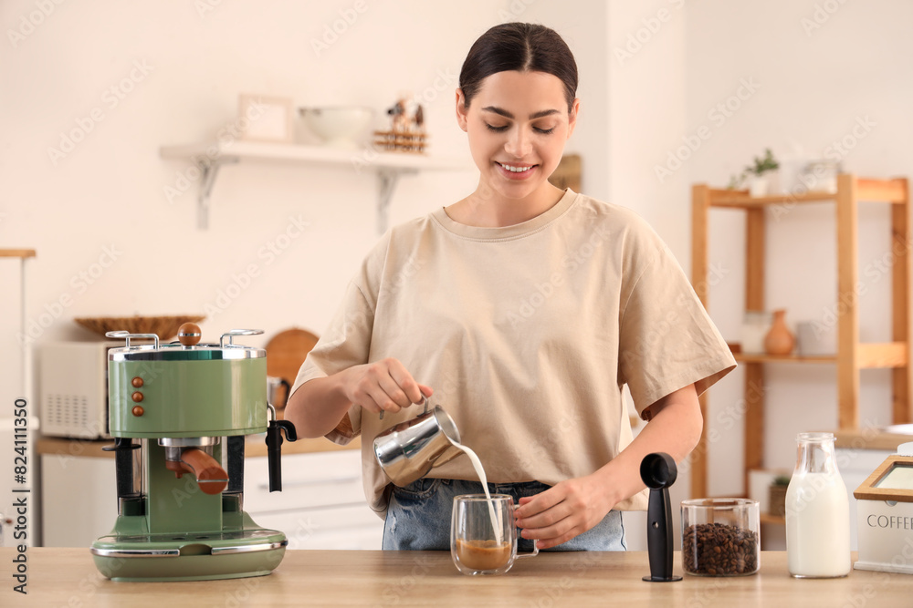 Beautiful young happy woman with modern machine pouring milk into cup of fresh coffee in kitchen Beautiful young happy woman with modern machine pouring milk into cup of fresh coffee in kitchen