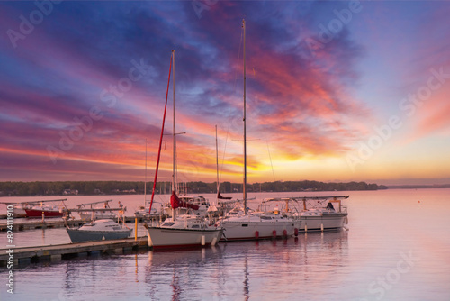 Several boats tied up at a yacht club pier during a spectacular colourful sunset, nobody