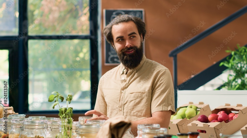 Portrait of client in sustainable market looking at pasta or grains stored in recyclable glass containers, local neighbourhood zero waste shop. Grocery store with organic chemicals free produce. Portrait of client in sustainable market looking at pasta or grains stored in recyclable glass containers, local neighbourhood zero waste shop. Grocery store with organic chemicals free produce.