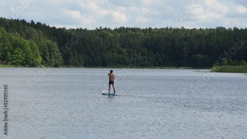 Man paddling on SUP board on beautiful lake during sunset or sunrise, standing up paddle boarding morning adventure in  lake. travel adventure water sport