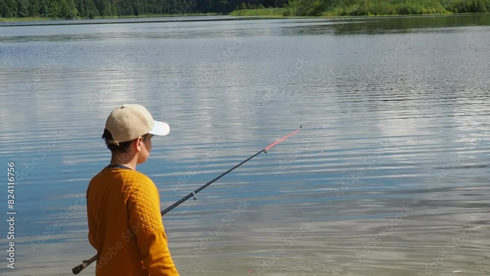 A little cute boy is fishing at a lake in summer. He holds the fishing rod bent in his hand and has a big catch. A fish jumps out of the water. The boy is surprised. active outdoor recreation A little cute boy is fishing at a lake in summer. He holds the fishing rod bent in his hand and has a big catch. A fish jumps out of the water. The boy is surprised. active outdoor recreation