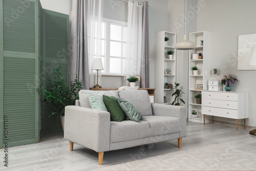 Interior of living room with green folding screen, sofa and shelf units photo
