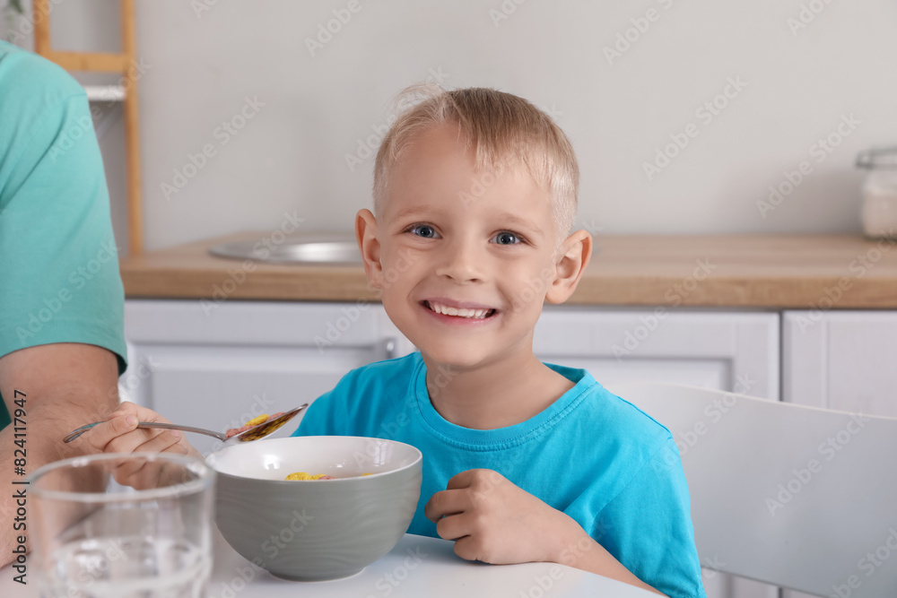 Happy little son and his father eating cornflakes with milk on breakfast at home Happy little son and his father eating cornflakes with milk on breakfast at home