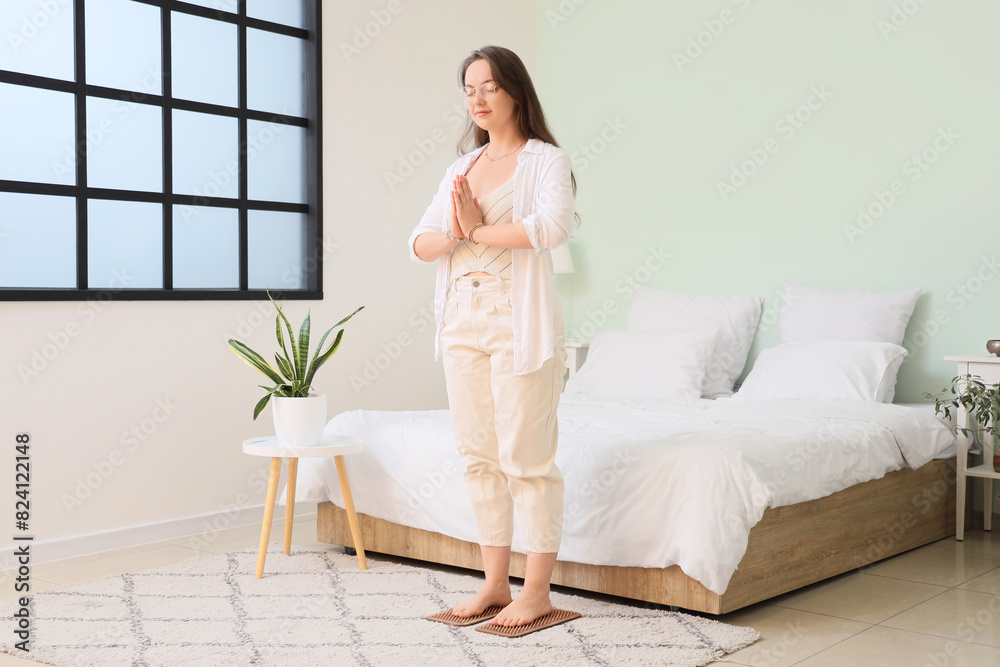 Young woman standing on Sadhu board in bedroom Young woman standing on Sadhu board in bedroom