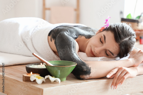 Young woman with mud lying ...