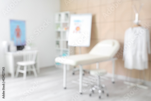 Blurred view of medical office with couch and doctor s workplace