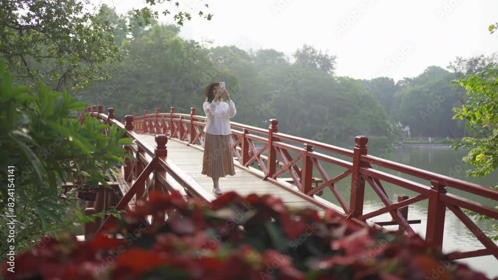Portrait of Asian Vietnamese woman travel in The Red Bridge in public park garden with trees in Hoan Kiem Lake in Downtown Hanoi. Urban city, Vietnam.. Portrait of Asian Vietnamese woman travel in The Red Bridge in public park garden with trees in Hoan Kiem Lake in Downtown Hanoi. Urban city, Vietnam..