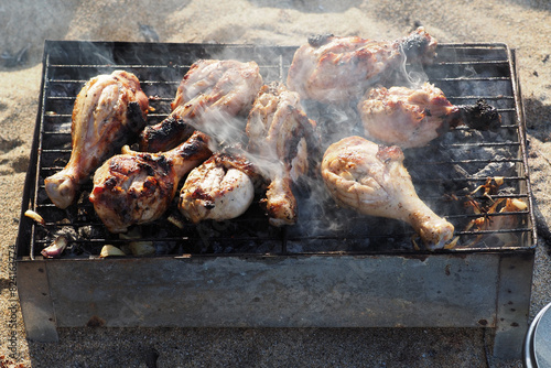 Cooking Chicken Pieces on Grill at Sandy Beach.