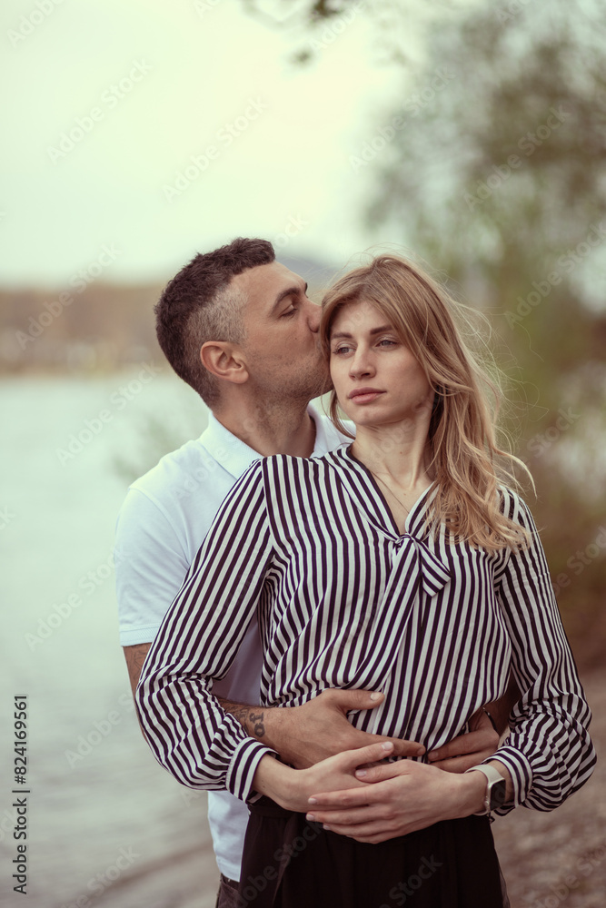 Obraz premium Couple standing by the river, man hugging woman.