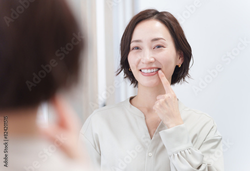 鏡を見て歯のチェックをするミドル女性（美容・歯列矯正・ホワイトニング） photo