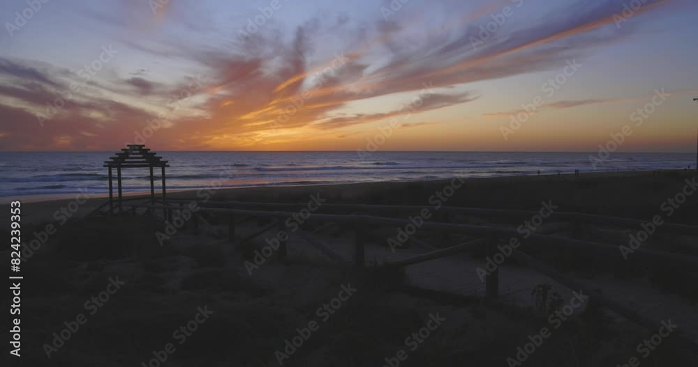 Tropical beach at sunset with dramatic ocean red and purple sky. People silhouette walking on costline with calm waves at dusk. Tropical beach at sunset with dramatic ocean red and purple sky. People silhouette walking on costline with calm waves at dusk.