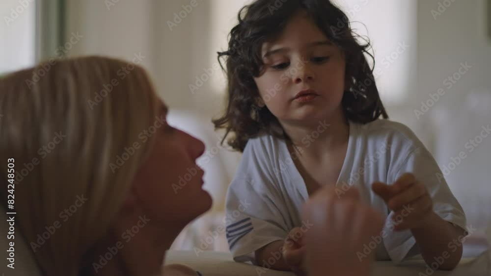 A young boy engages in a conversation with his mother while indoors. Both are comfortably dressed, emphasizing a warm and intimate dialogue. A young boy engages in a conversation with his mother while indoors. Both are comfortably dressed, emphasizing a warm and intimate dialogue.