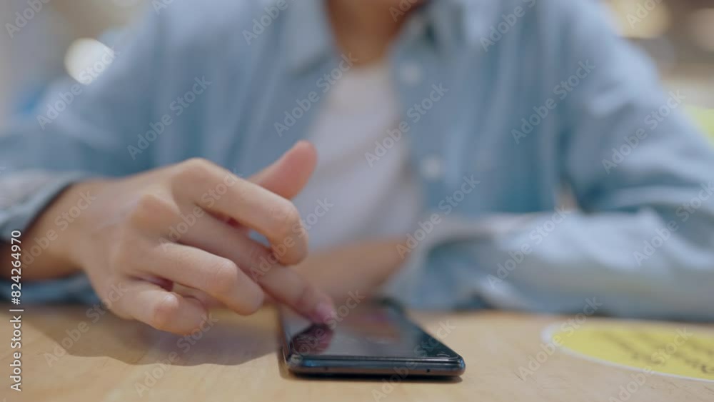 A person is giving a thumbs up to a cell phone. The phone is on a table and the person is sitting on a chair