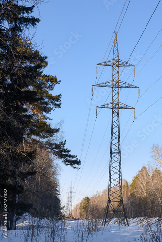 High iron towers for high-voltage power lines in a clearing in the winter forest