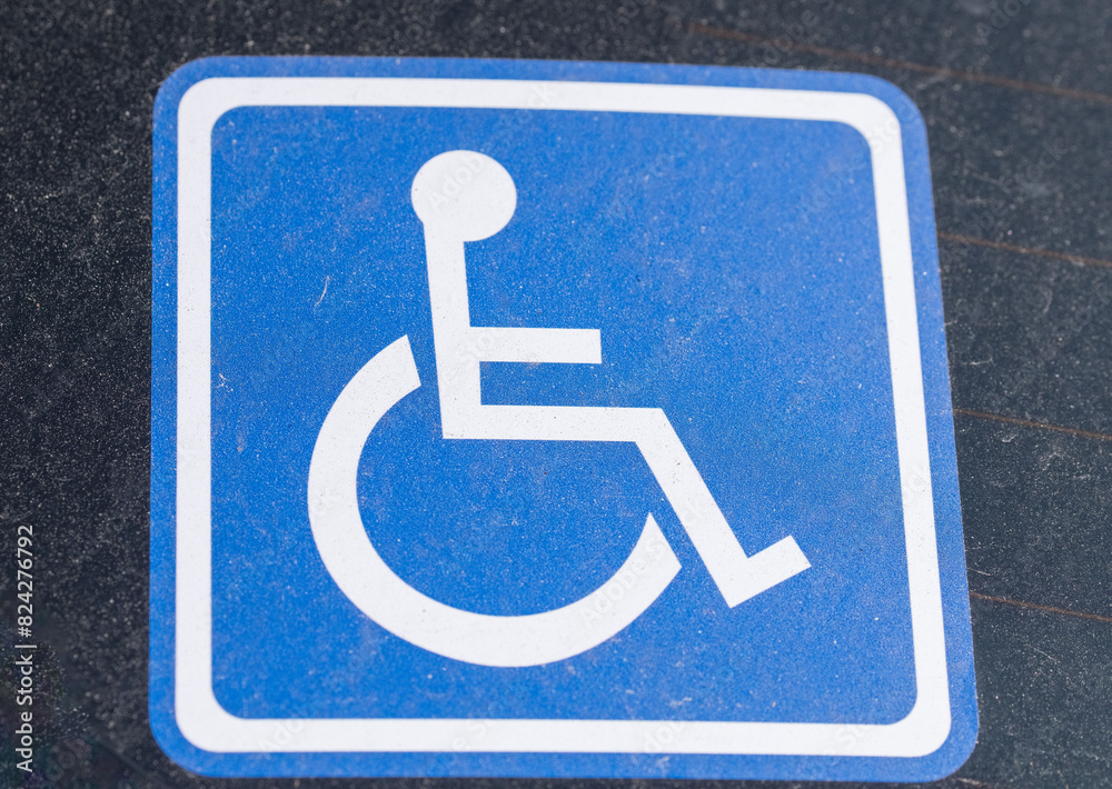 Ein blaues Behindertenschild hinter der Autoscheibe Ein blaues Behindertenschild hinter der Autoscheibe