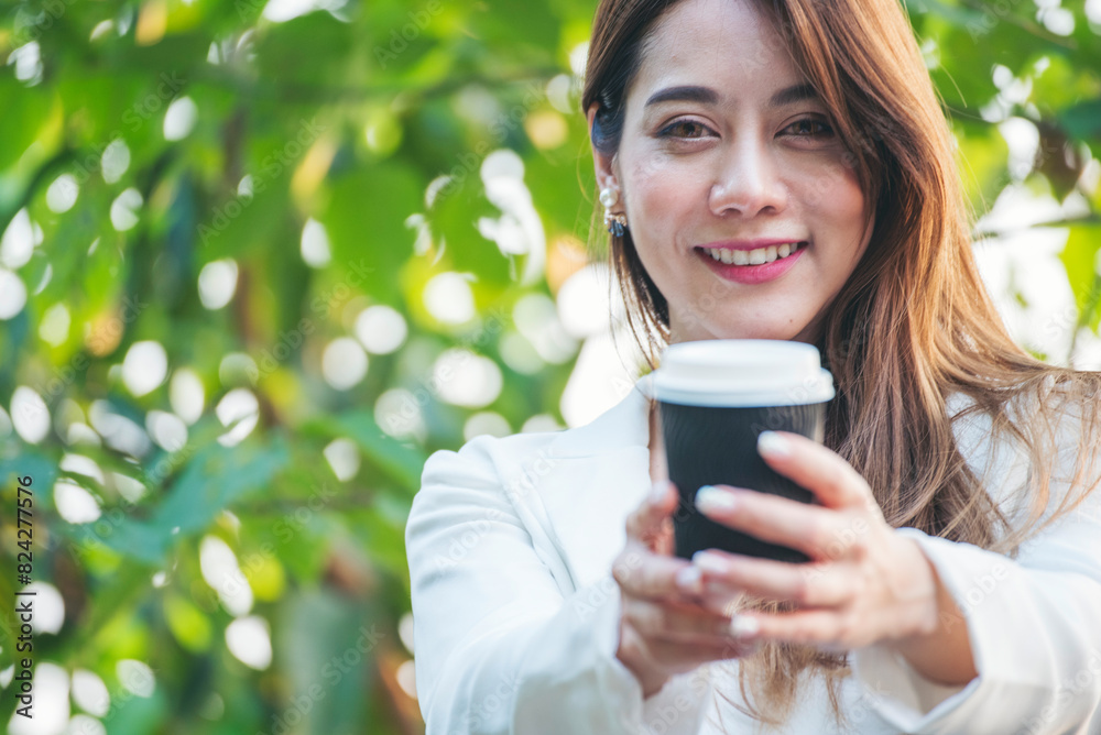 Woman drinking coffee hands holding hot disposable cup in green park. Happy Relax beautiful asian woman smiling face standing outdoors garden. Young women enjoy nature morning Freedom Lifestyle.