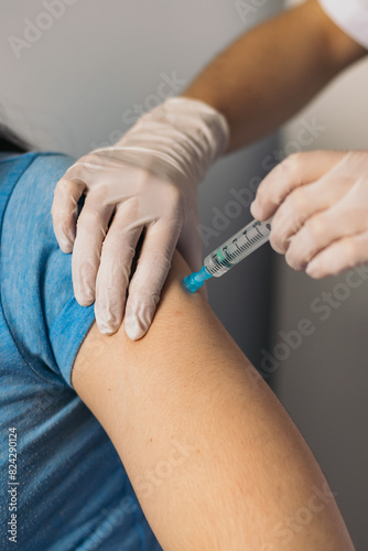 Doctor hands injecting vaccine in the arm of a patient.