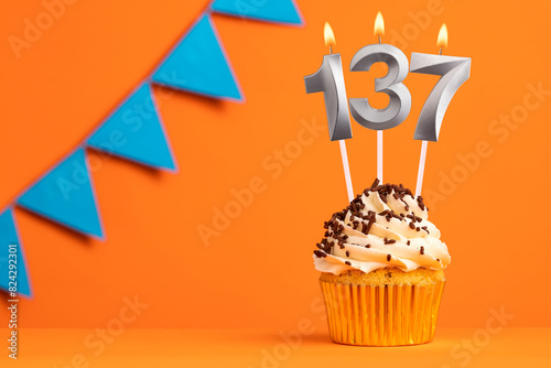 Birthday cupcake with candle number 137 - Orange background