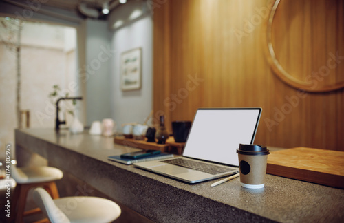 Comfortable workplace on counter bar in cafe with take away coffee cup, laptop, note book and mobile, warm color tone