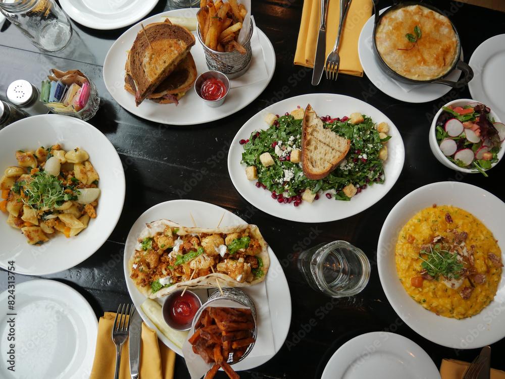 Various lunch dishes, fresh American food. Dark background. Top view. House salad, cauliflower tacos, sandwich, fries, souffle, cheese risotto. Healthy eating, farm to table. Various lunch dishes, fresh American food. Dark background. Top view. House salad, cauliflower tacos, sandwich, fries, souffle, cheese risotto. Healthy eating, farm to table.