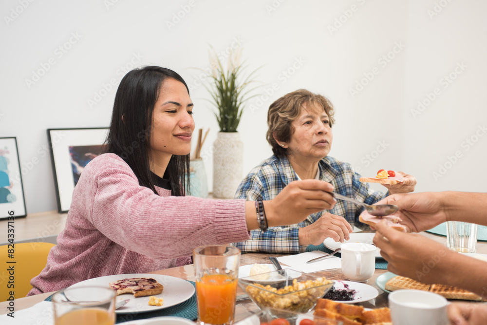 Mature mother and young daughter eating breakfast together at home Mature mother and young daughter eating breakfast together at home