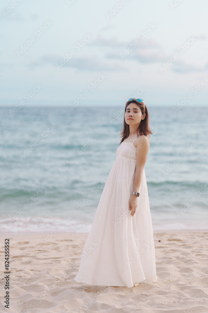 Happy traveler woman in white dress enjoy beautiful sea view, young woman standing on sand and looking ocean at tropical beach. Freedom, relaxing, vacation holiday and summer travel concept Happy traveler woman in white dress enjoy beautiful sea view, young woman standing on sand and looking ocean at tropical beach. Freedom, relaxing, vacation holiday and summer travel concept