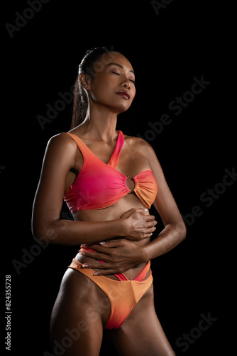 Fashionable asion woman in a bikini  poing in the studio