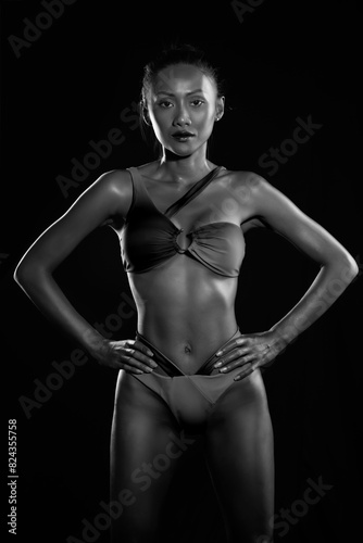
fashion model in bikini posing on black background, black and white 