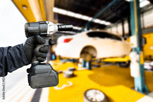 Car repair and maintenance servicing concept , Hand of an auto mechanic using a cordless impact wrench in a car repair facility center