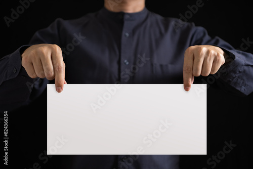 The hand of an Asian working man is holding a blank white sheet of paper for filling in text.