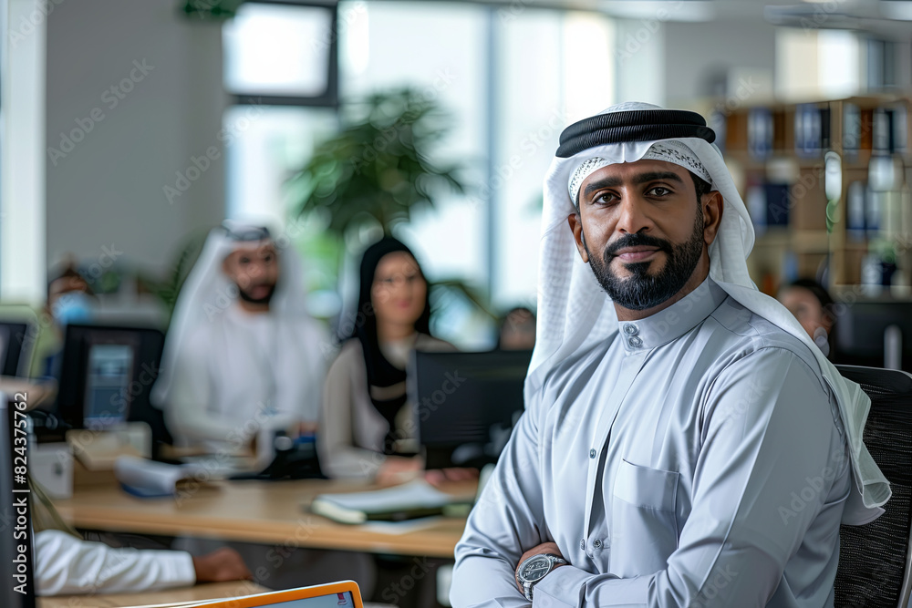 Emirati businessman in Kandura at office with colleagues
Emirati businessman in Kandura at office with colleagues