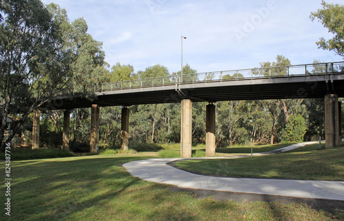 Bridge over the Mehi River with trees, grass, pathway and sky in Moree, New South Wales, Australia