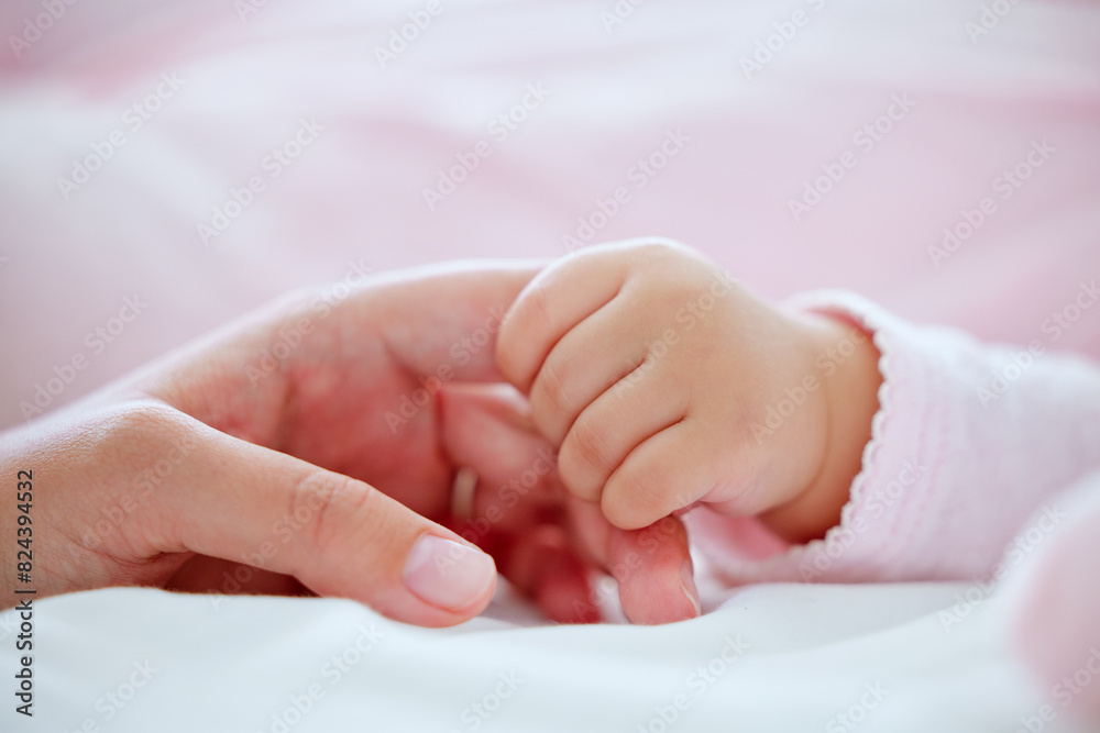 Baby, mother and holding hands with closeup in bed with care, connection and love in morning in home. Mom, infant child and together with bonding, development and growth in nursery at family house Baby, mother and holding hands with closeup in bed with care, connection and love in morning in home. Mom, infant child and together with bonding, development and growth in nursery at family house