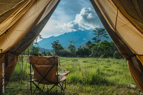 Fototapeta Naklejka Na Ścianę i Meble -  View from inside a canvas tent opening onto a tranquil meadow with a majestic mountain backdrop, inviting exploration and relaxation